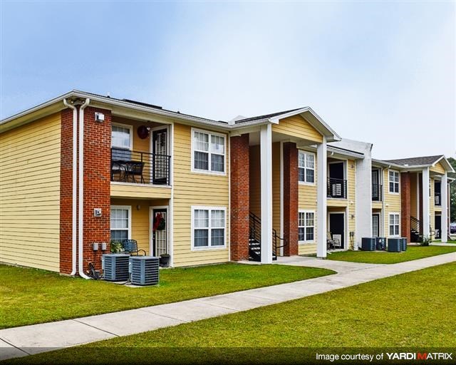 a row of apartment buildings with a sidewalk and grass