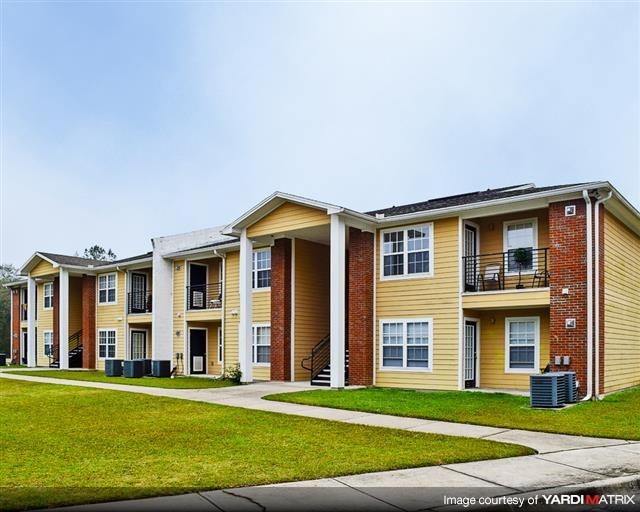 an apartment building with a green lawn and a sidewalk