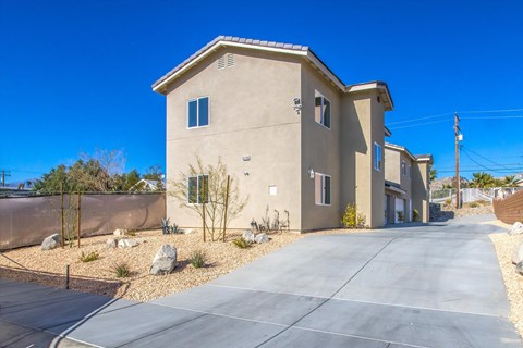 A beige house with a grey roof and a driveway in front.