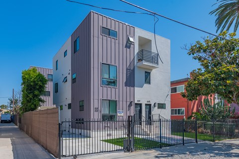 A modern building with a grey facade and a black fence in front.
