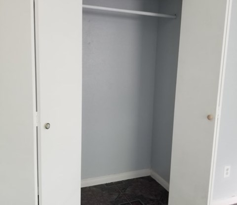 A white closet with a door and a shelf.