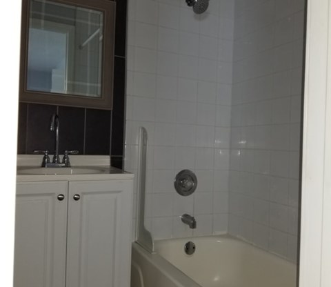 A white bathroom with a sink and a shower.