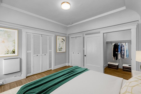 A bedroom with a bed, wardrobe, and a painting on the wall.