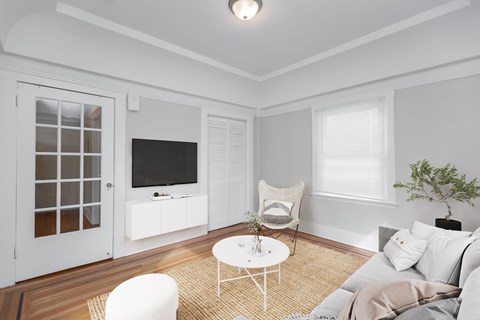 A white chair sits in a living room with a television and a plant.