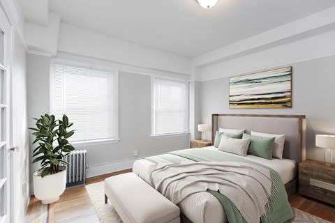 A bedroom with a large bed and a potted plant.