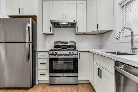 A modern kitchen with a stainless steel refrigerator, oven, and cabinets.