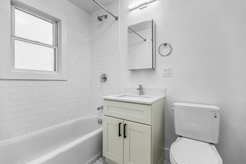 A white bathroom with a tub, toilet, sink, and medicine cabinet.