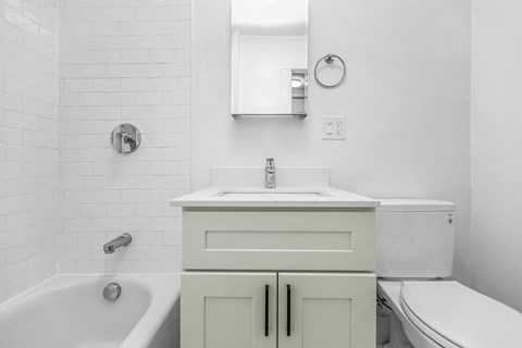 A white bathroom with a tub, sink, and toilet.