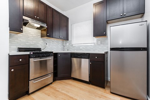 A kitchen with dark wood cabinets and stainless steel appliances.