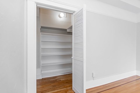 A white shelving unit is open in a room with wood flooring.