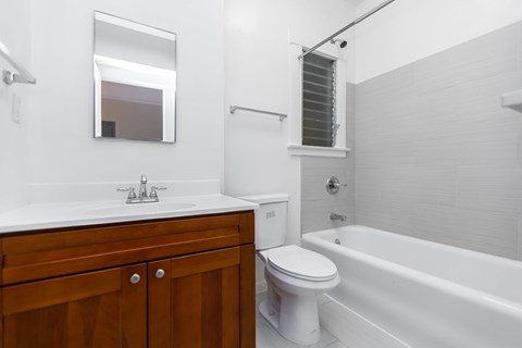 A white toilet sits next to a white bathtub in a bathroom.