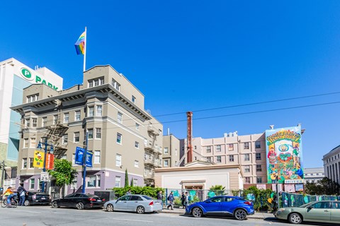 A street view with cars, a building with a PARK sign, and a flag on top.