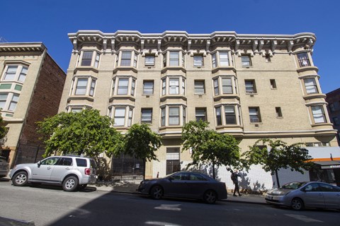 A street view of a building with cars parked in front.