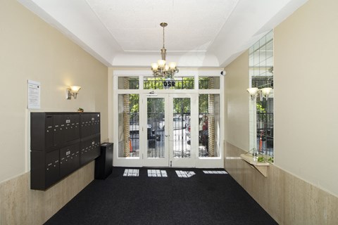 A hallway with a black carpet and a chandelier hanging from the ceiling.