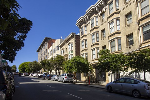 A street view of a residential area with cars parked on the side of the road.