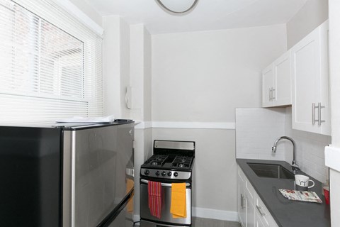 A black refrigerator is in a kitchen next to a stove.