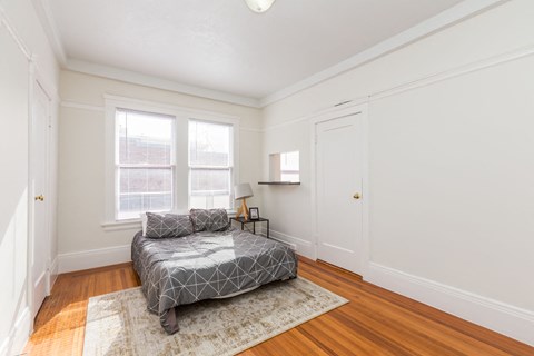 A bedroom with a bed and a rug in the center.
