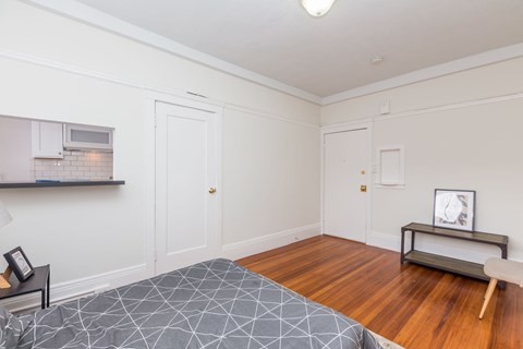 A bedroom with a bed, a bench, and a microwave on the counter.