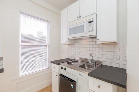 A kitchen with white cabinets and a black countertop.