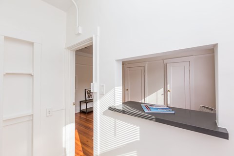 A white hallway with a black bench and a picture frame on a table.