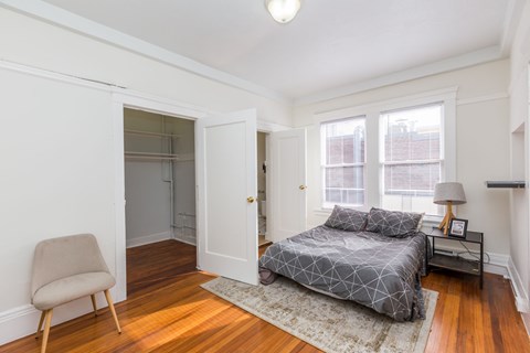 A bedroom with a bed, chair, and window.