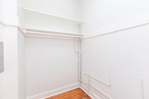 A white wall with a pipe and a wooden floor.