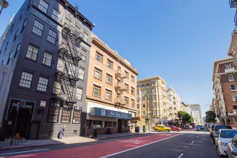 A city street with a red bike lane and parked cars.