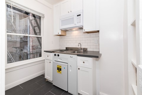 A kitchen with white cabinets and a black countertop.