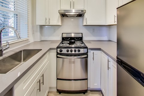 A modern kitchen with a stainless steel stove and white cabinets.
