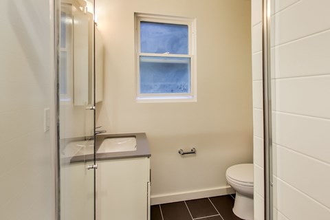 A small bathroom with a toilet, sink, and a window.