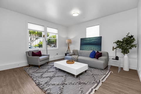 A living room with a grey couch, a white coffee table, and a painting on the wall.