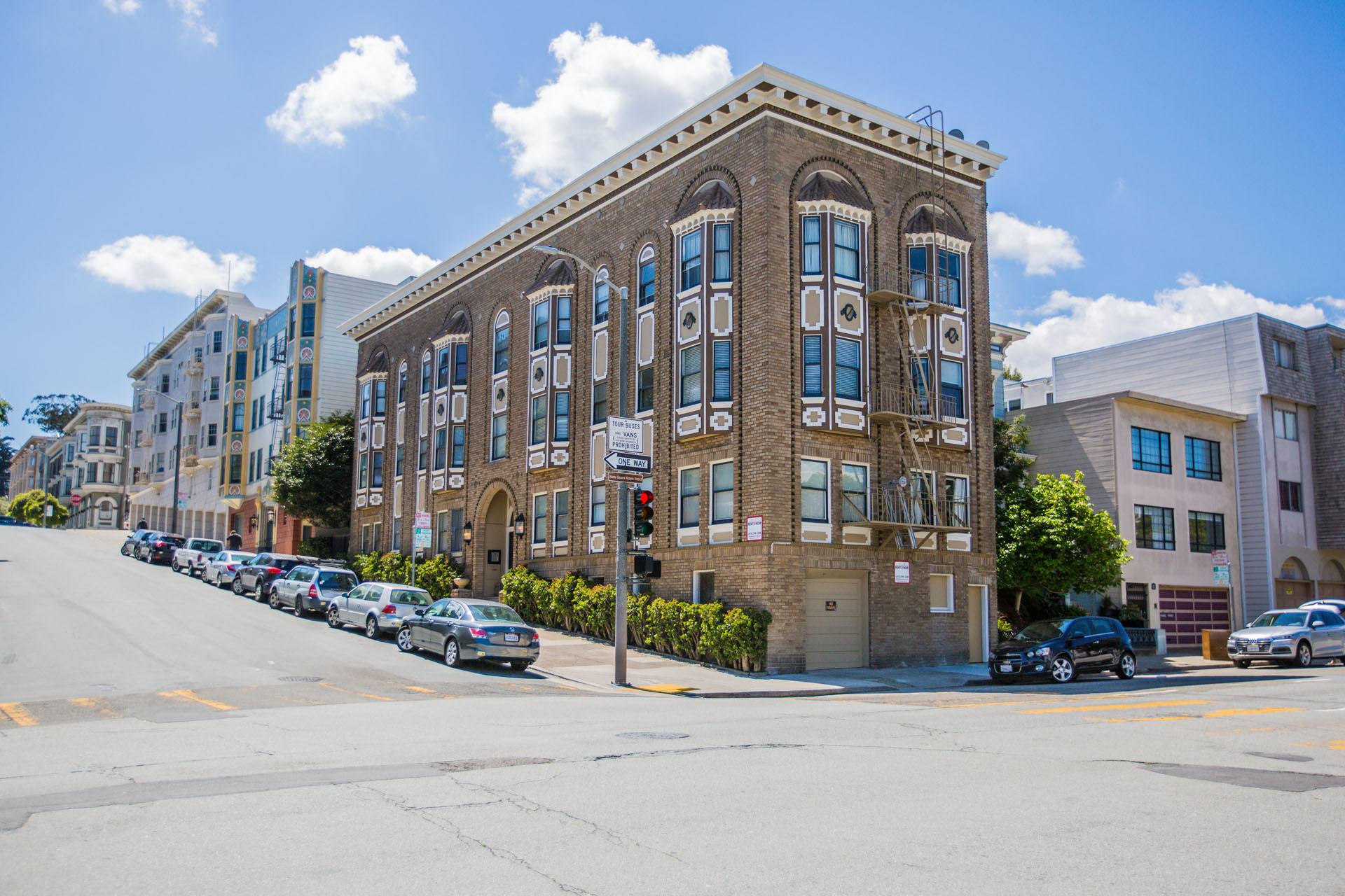 A street view of a row of buildings with cars parked on the side.