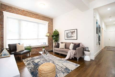 A living room with a couch, a chair, a table, and a rug.
