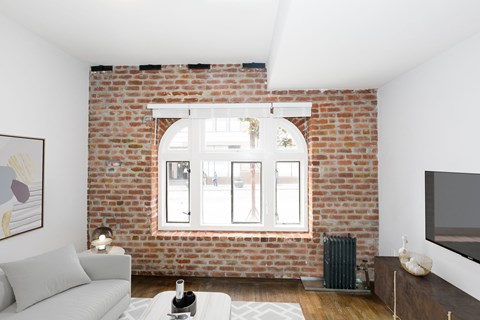 A living room with a white couch and a brick wall.
