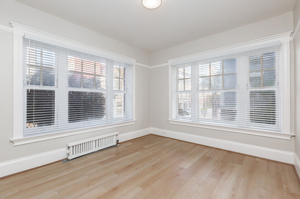 a living room with two windows and a wood floor
