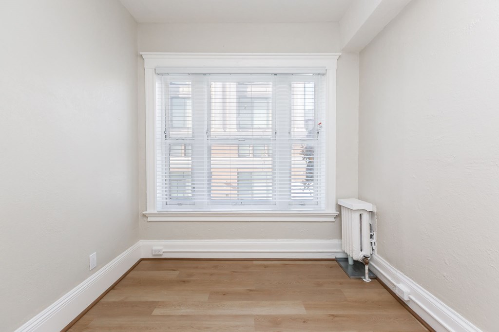 a small room with a window and a wooden floor