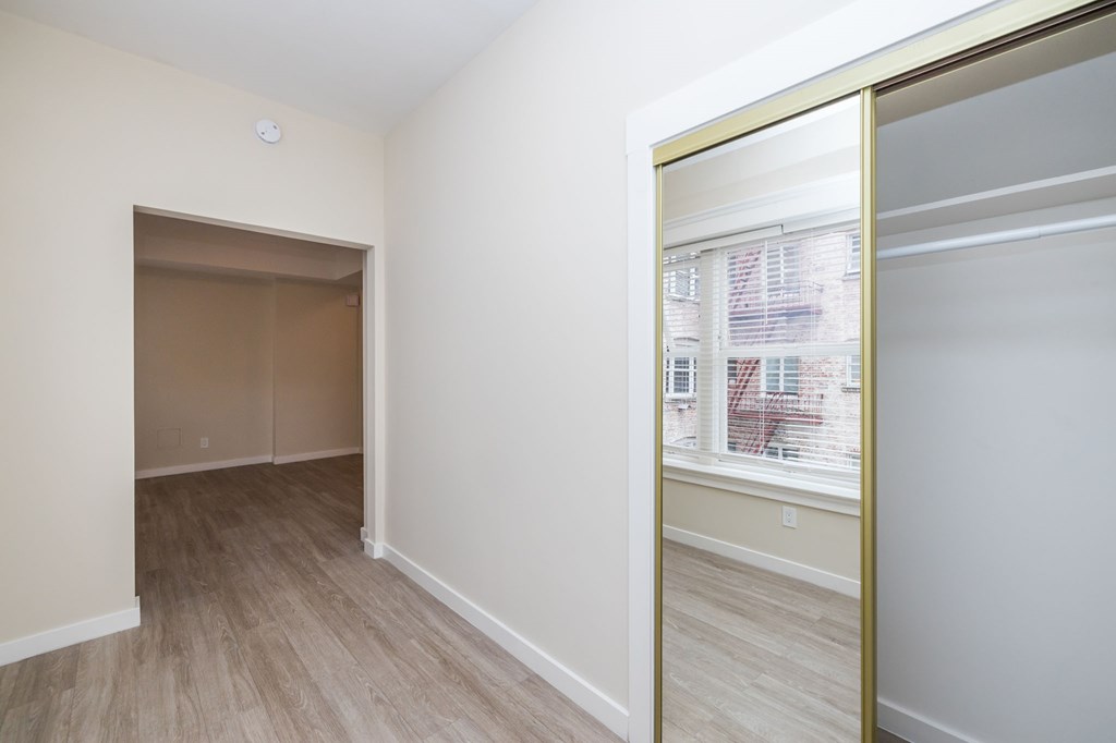 a bedroom with a large window and a mirrored closet