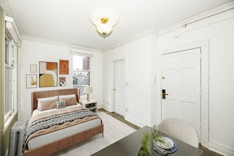 A bedroom with a bed, nightstand, and a table with a plant on it.