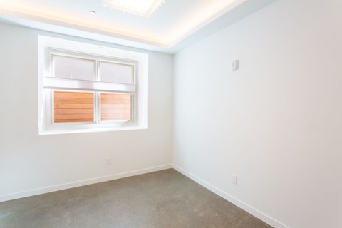 A room with a window and a light switch on the wall.