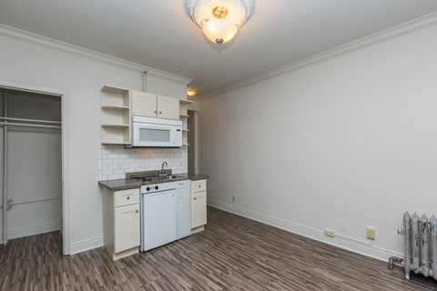 A kitchen with white cabinets and a wooden floor.