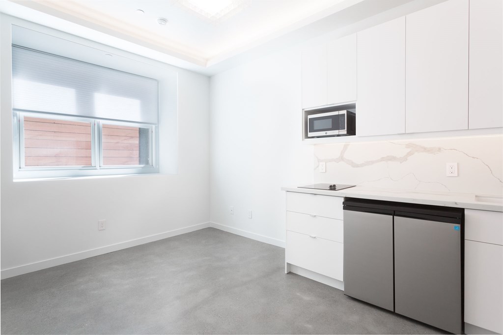 an empty kitchen with white cabinets and a window