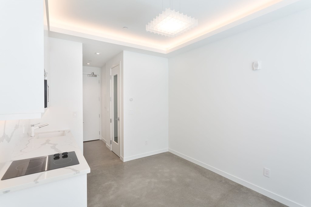 a living room with white walls and a kitchen with white counter tops and a sink