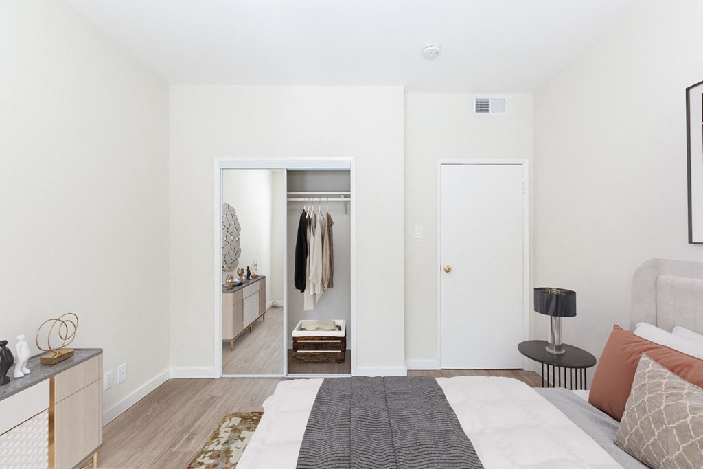 A bedroom with a bed, a nightstand, a dresser, a wardrobe, and a rug.