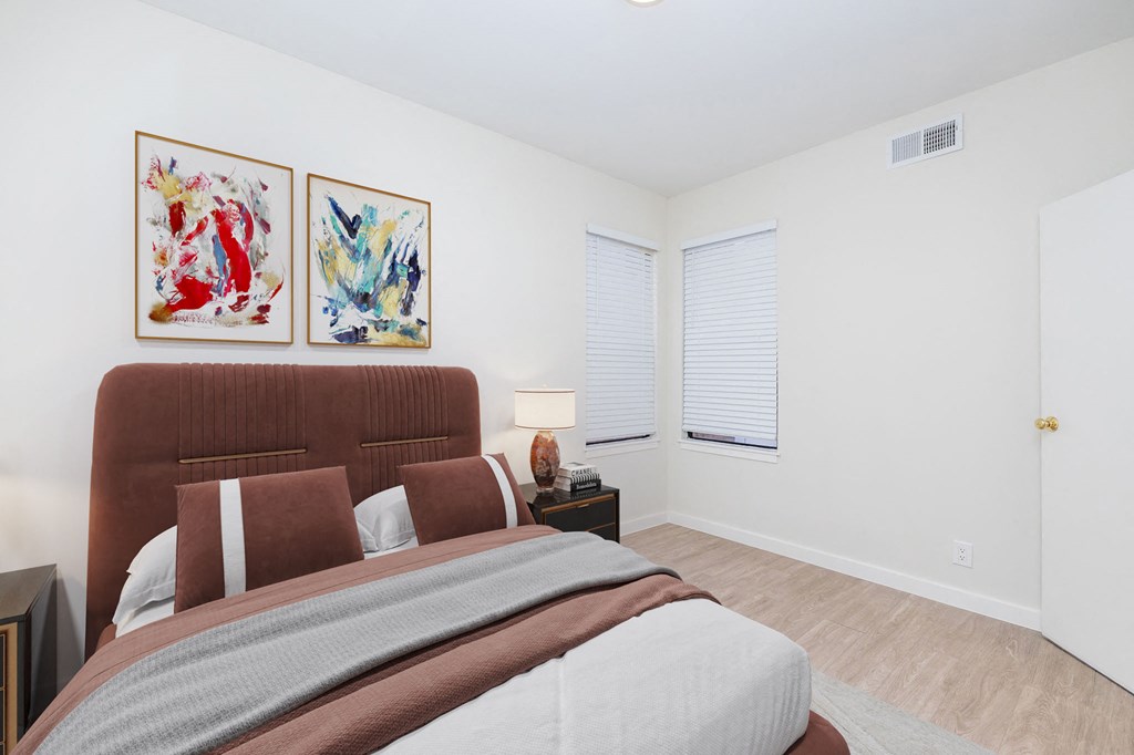 A bedroom with a large bed and two framed pictures on the wall.