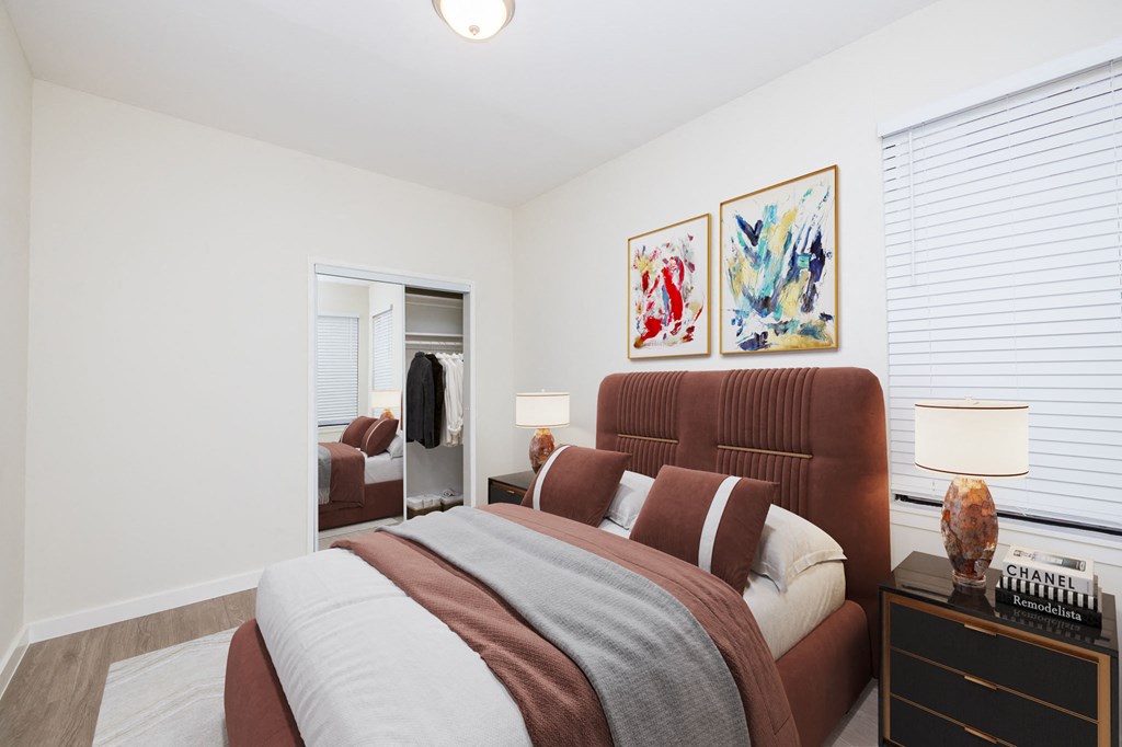 A bedroom with a large bed and a dresser with a lamp on top.