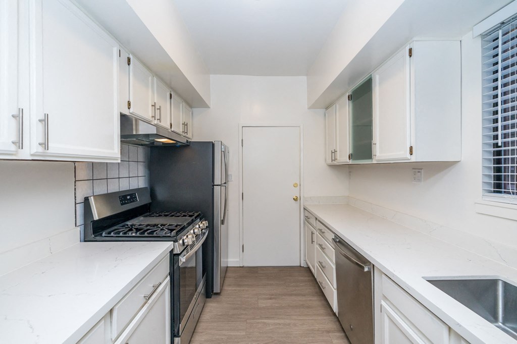 A kitchen with white cabinets and a black refrigerator.