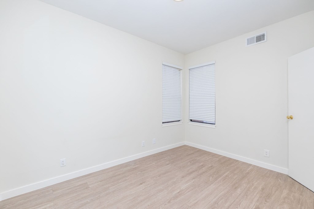 A room with a wooden floor and a door on the right side.