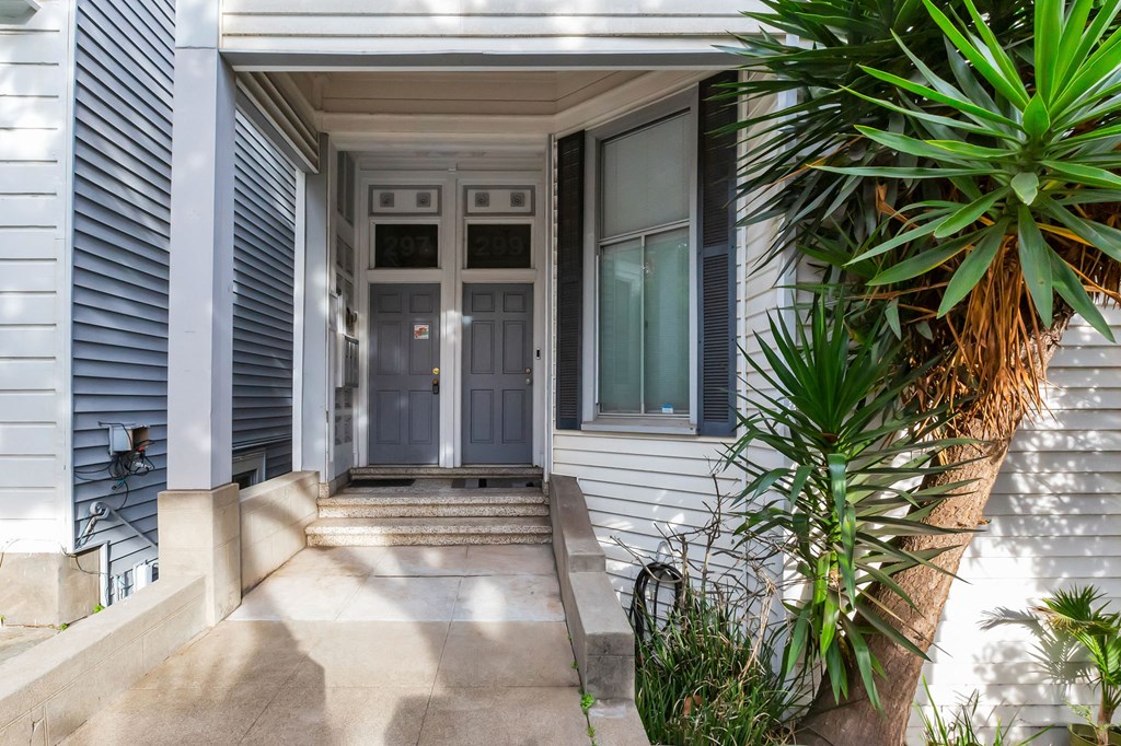 A house entrance with a grey door and steps leading up to it.
