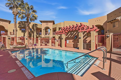 A pool surrounded by a red fence and a building with a red roof.