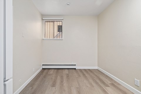 A room with a window and wooden flooring.